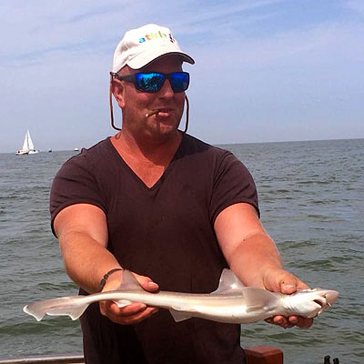 Blije man die haai vasthoudt die hij heeft gevangen oin Zeeland Blije man die haai vasthoudt die hij heeft gevangen oin Zeeland