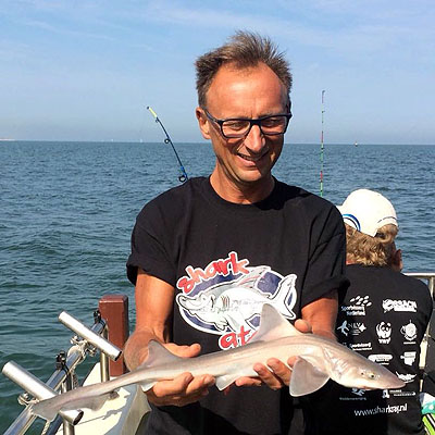 Gelukkige man die haai vasthoudt die hij heeft gevangen op de Noordzee Gelukkige man die haai vasthoudt die hij heeft gevangen op de Noordzee